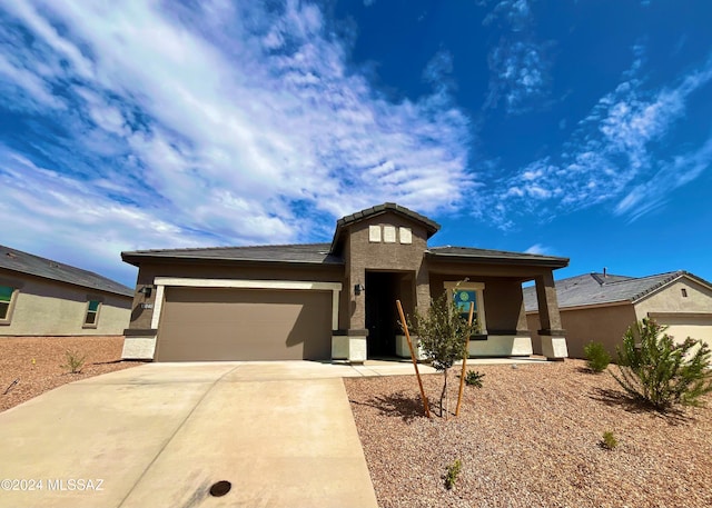 prairie-style home featuring driveway, an attached garage, and stucco siding