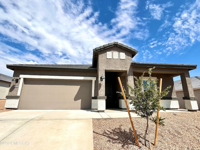 prairie-style home featuring a garage, concrete driveway, and stucco siding