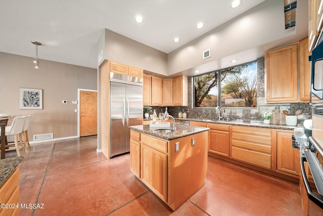 kitchen featuring a center island with sink, decorative backsplash, concrete flooring, and stainless steel appliances