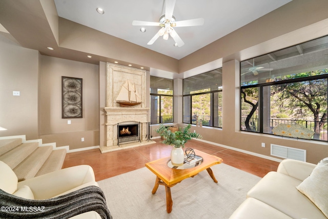 tiled living room with ceiling fan and a fireplace