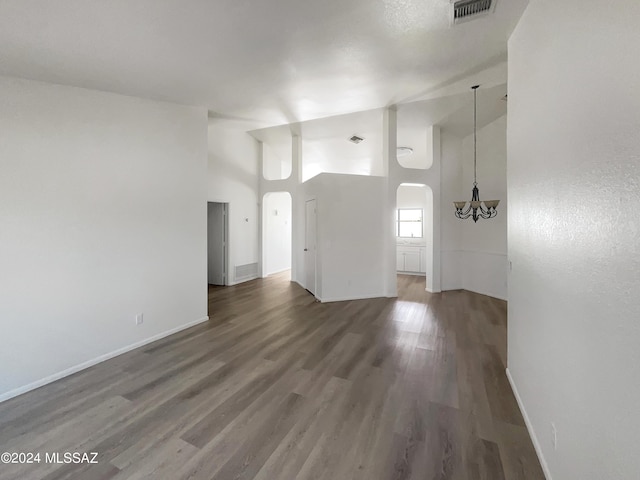 unfurnished living room featuring dark hardwood / wood-style floors, high vaulted ceiling, and a notable chandelier