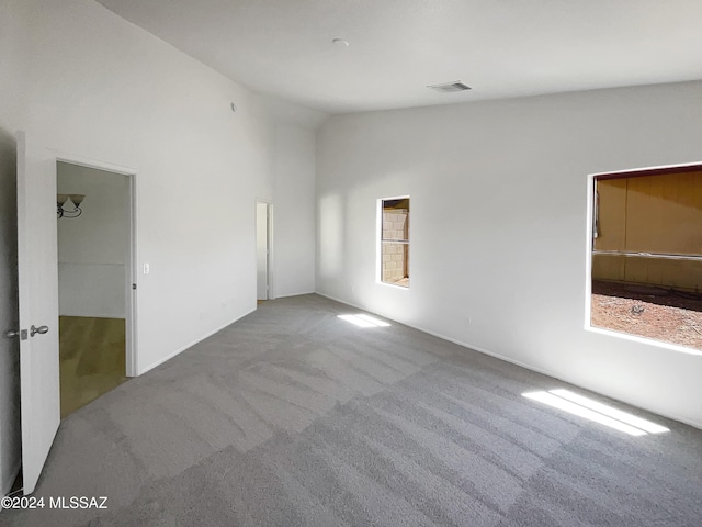 carpeted empty room with vaulted ceiling