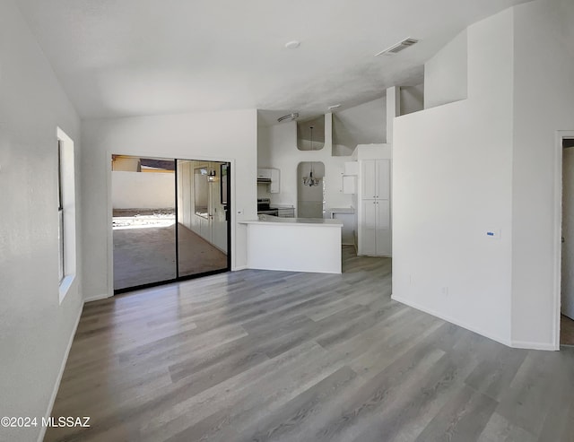 unfurnished living room with light hardwood / wood-style floors and high vaulted ceiling