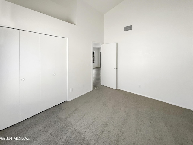 unfurnished bedroom with light carpet, a closet, and high vaulted ceiling