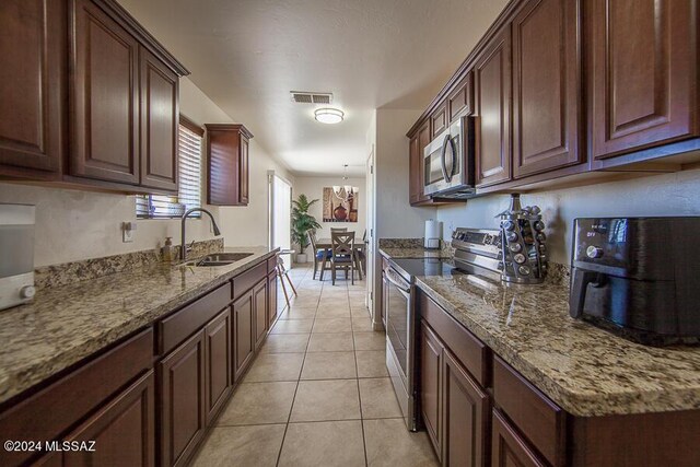 kitchen featuring light tile patterned floors, stone counters, visible vents, a sink, and stainless steel appliances