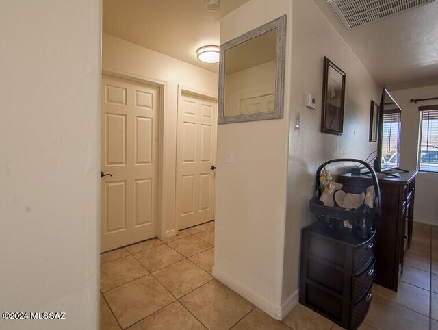 corridor featuring light tile patterned floors, visible vents, and baseboards