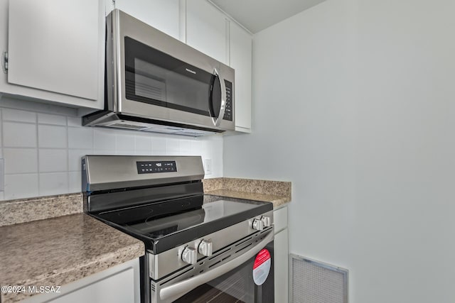 kitchen featuring white cabinets, appliances with stainless steel finishes, and backsplash