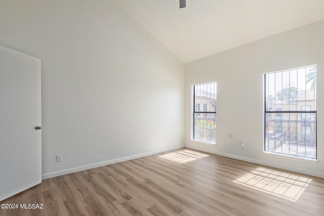 empty room with light hardwood / wood-style flooring, high vaulted ceiling, and plenty of natural light