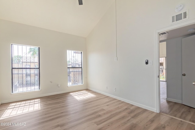 empty room featuring high vaulted ceiling, light hardwood / wood-style flooring, and ceiling fan