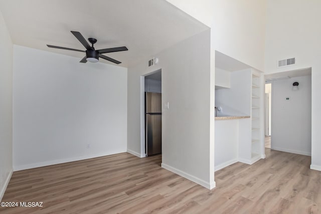 unfurnished room featuring ceiling fan, built in shelves, and light hardwood / wood-style flooring