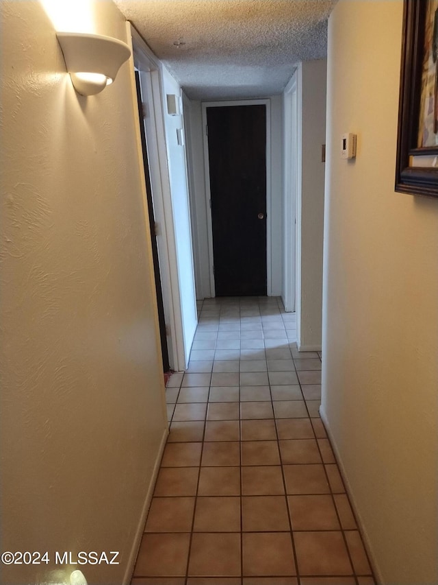 hall with tile patterned flooring and a textured ceiling