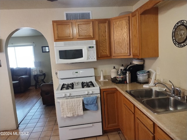 kitchen featuring light tile patterned floors, white appliances, and sink