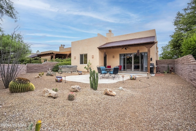 back of house with ceiling fan, a patio, and a hot tub