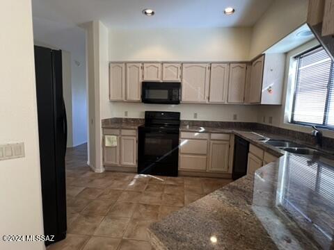 kitchen featuring sink, black appliances, dark stone counters, and tile patterned flooring