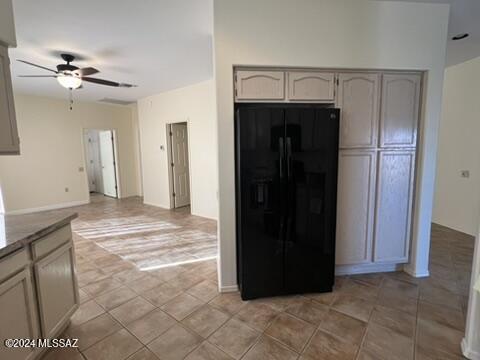 kitchen with light tile patterned flooring, ceiling fan, and black fridge