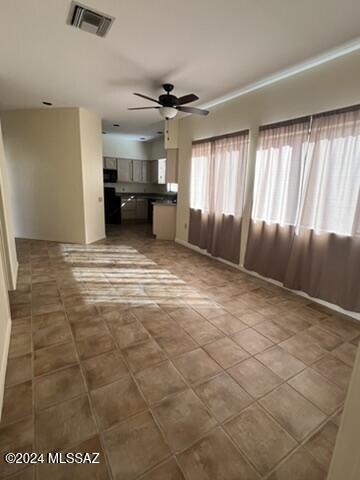 unfurnished living room featuring ceiling fan and tile patterned flooring