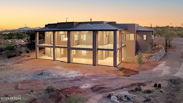 back house at dusk with a balcony and a patio area