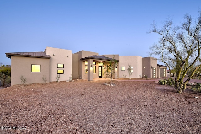 back house at dusk featuring a garage