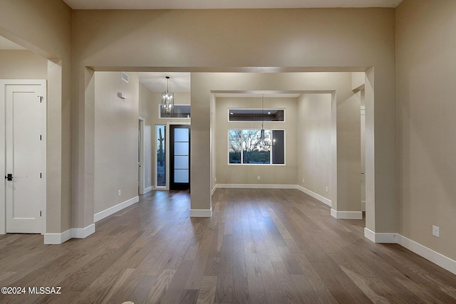 spare room with an inviting chandelier and hardwood / wood-style floors