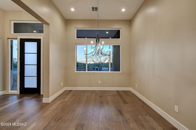 unfurnished dining area with hardwood / wood-style flooring and a chandelier