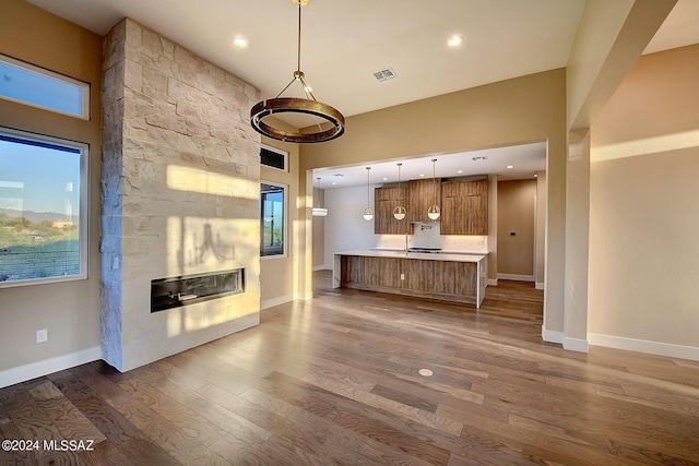 unfurnished living room with a stone fireplace, a towering ceiling, and dark hardwood / wood-style floors