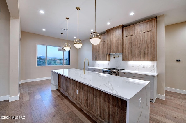 kitchen with decorative light fixtures, a large island, light stone counters, high end stainless steel range oven, and light wood-type flooring