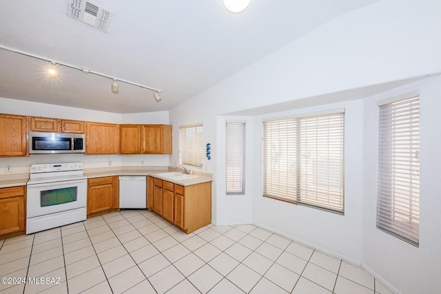 kitchen with lofted ceiling, white appliances, sink, and light tile patterned floors