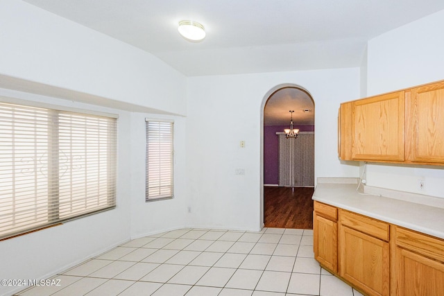 kitchen featuring a chandelier, light tile patterned flooring, pendant lighting, and lofted ceiling