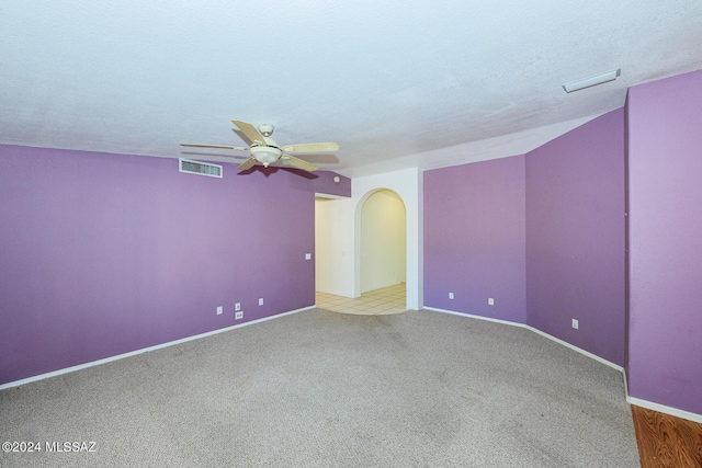 unfurnished room featuring lofted ceiling, ceiling fan, carpet floors, and a textured ceiling