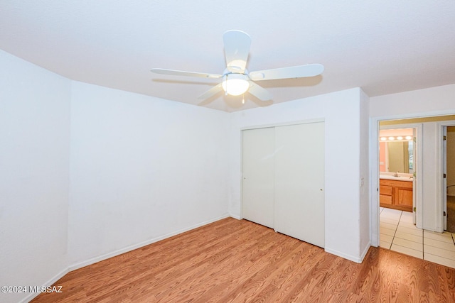 unfurnished bedroom with ceiling fan, light wood-type flooring, and a closet