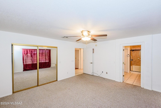 unfurnished bedroom with ceiling fan, a closet, light carpet, and a textured ceiling