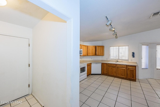 kitchen featuring sink, lofted ceiling, track lighting, white appliances, and light tile patterned floors