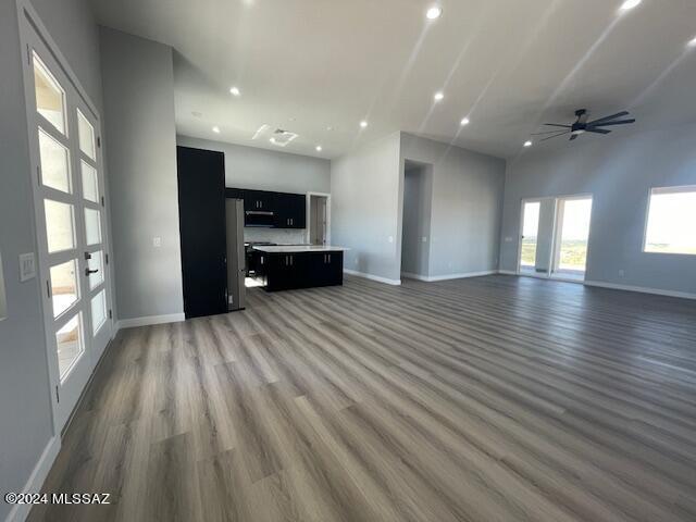 unfurnished living room featuring ceiling fan, hardwood / wood-style floors, and a towering ceiling