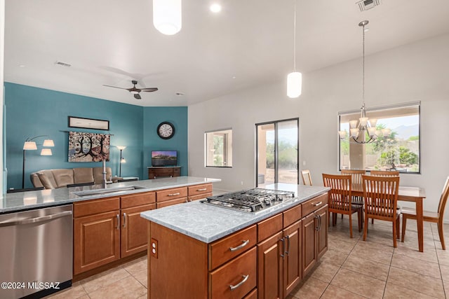 kitchen featuring sink, light tile patterned floors, stainless steel appliances, a center island, and decorative light fixtures