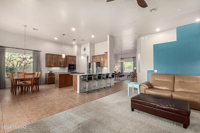 living room with light tile patterned floors, ceiling fan with notable chandelier, and a towering ceiling