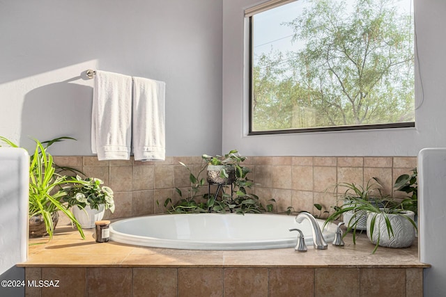 bathroom with tiled tub and a healthy amount of sunlight