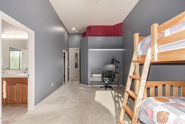 carpeted bedroom featuring sink, ensuite bath, and a high ceiling