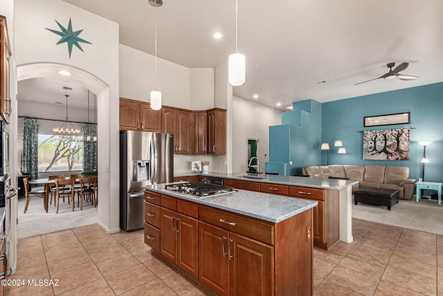 kitchen featuring light colored carpet, appliances with stainless steel finishes, open floor plan, a center island, and a sink