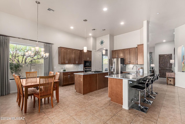 kitchen with a breakfast bar, appliances with stainless steel finishes, kitchen peninsula, pendant lighting, and a towering ceiling