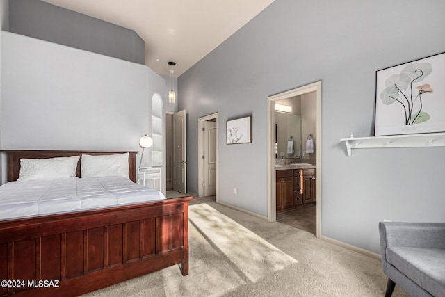 bedroom with arched walkways, light carpet, connected bathroom, a sink, and baseboards