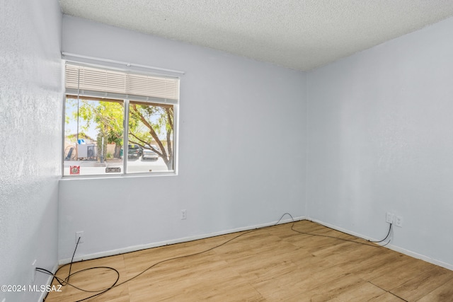 unfurnished room with light hardwood / wood-style floors and a textured ceiling