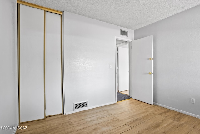 unfurnished bedroom featuring a closet, light hardwood / wood-style flooring, and a textured ceiling