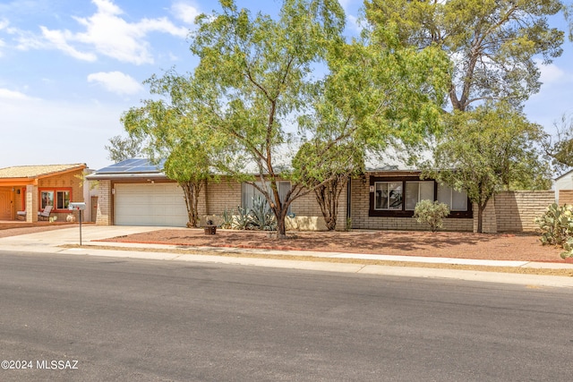 ranch-style home featuring solar panels and a garage