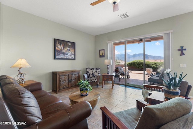 living room featuring a mountain view, light tile patterned floors, and ceiling fan