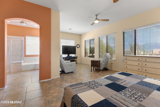 tiled bedroom with connected bathroom, multiple windows, and ceiling fan