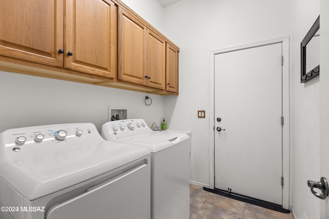 clothes washing area with washer and clothes dryer, light tile patterned floors, and cabinets