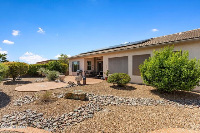 rear view of property with a patio area and solar panels