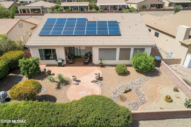 rear view of house with solar panels and a patio