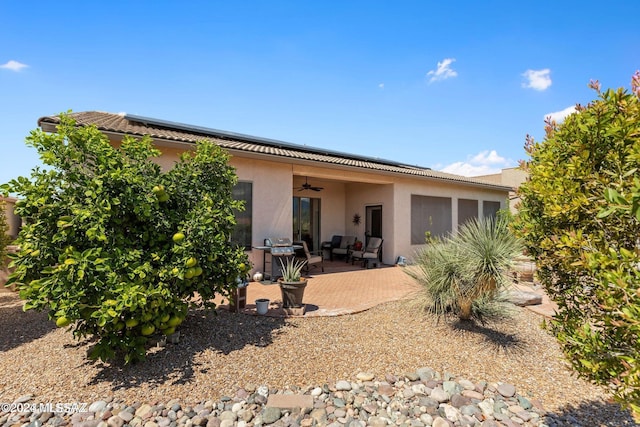 rear view of property featuring ceiling fan and a patio area