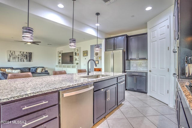 kitchen featuring sink, stainless steel appliances, dark brown cabinetry, tasteful backsplash, and decorative light fixtures